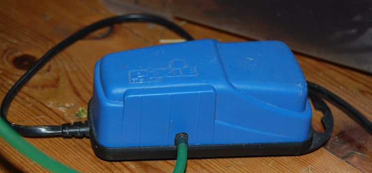 Aquariumspullen van Temu en AliExpress: een koopje of een miskoop? Een blauwe aquariumluchtpomp met aangesloten luchtslang op een houten ondergrond.