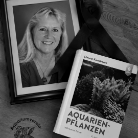 Herdenkingsbeeld met een portret van Christel Kasselmann, een rouwlint en haar boek Aquarienpflanzen