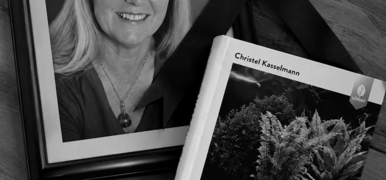 Herdenkingsbeeld met een portret van Christel Kasselmann, een rouwlint en haar boek Aquarienpflanzen